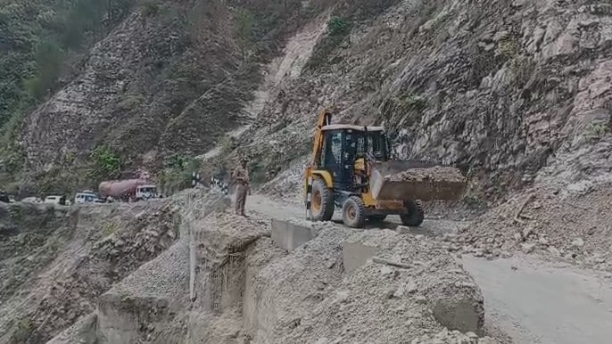 Cars wait as a JCB machine is clearing debris off the highway Cars wait as a JCB machine is clearing debris off the highway